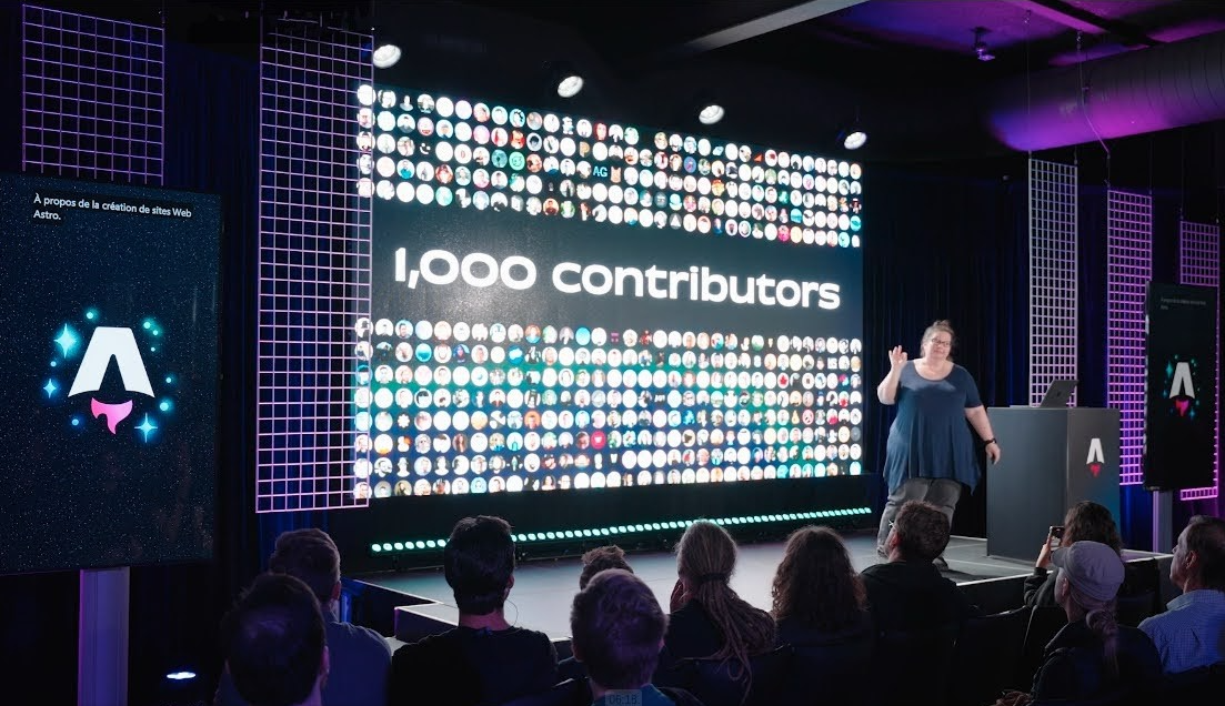 Sarah onstage giving a conference talk with a slide reading 1000 contributors surrounded by hundreds of GitHub avatars